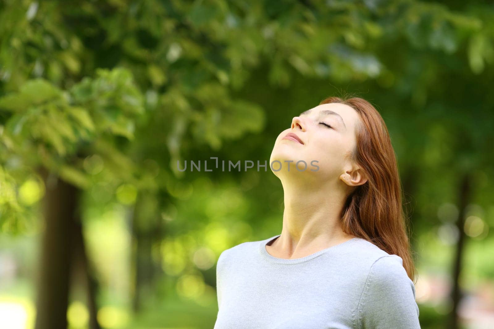 Beautiful woman relaxing breathing fresh air standing in a park