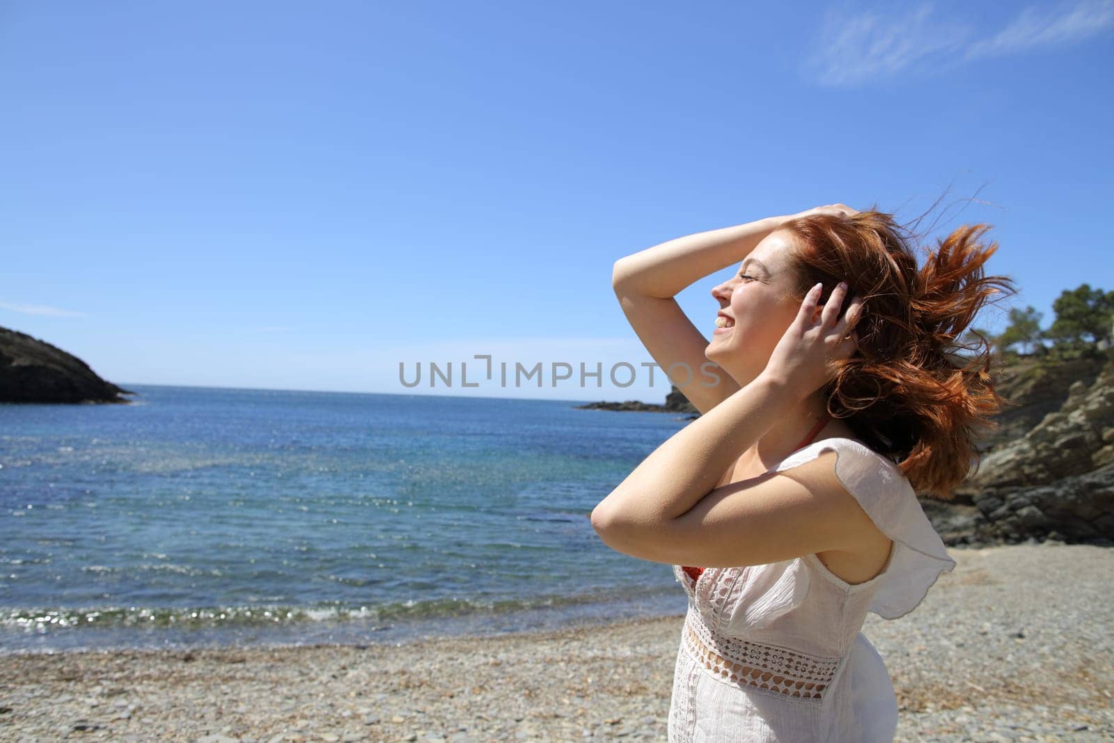 Happy woman touching tousled hair in a windy beach day on summer vacation