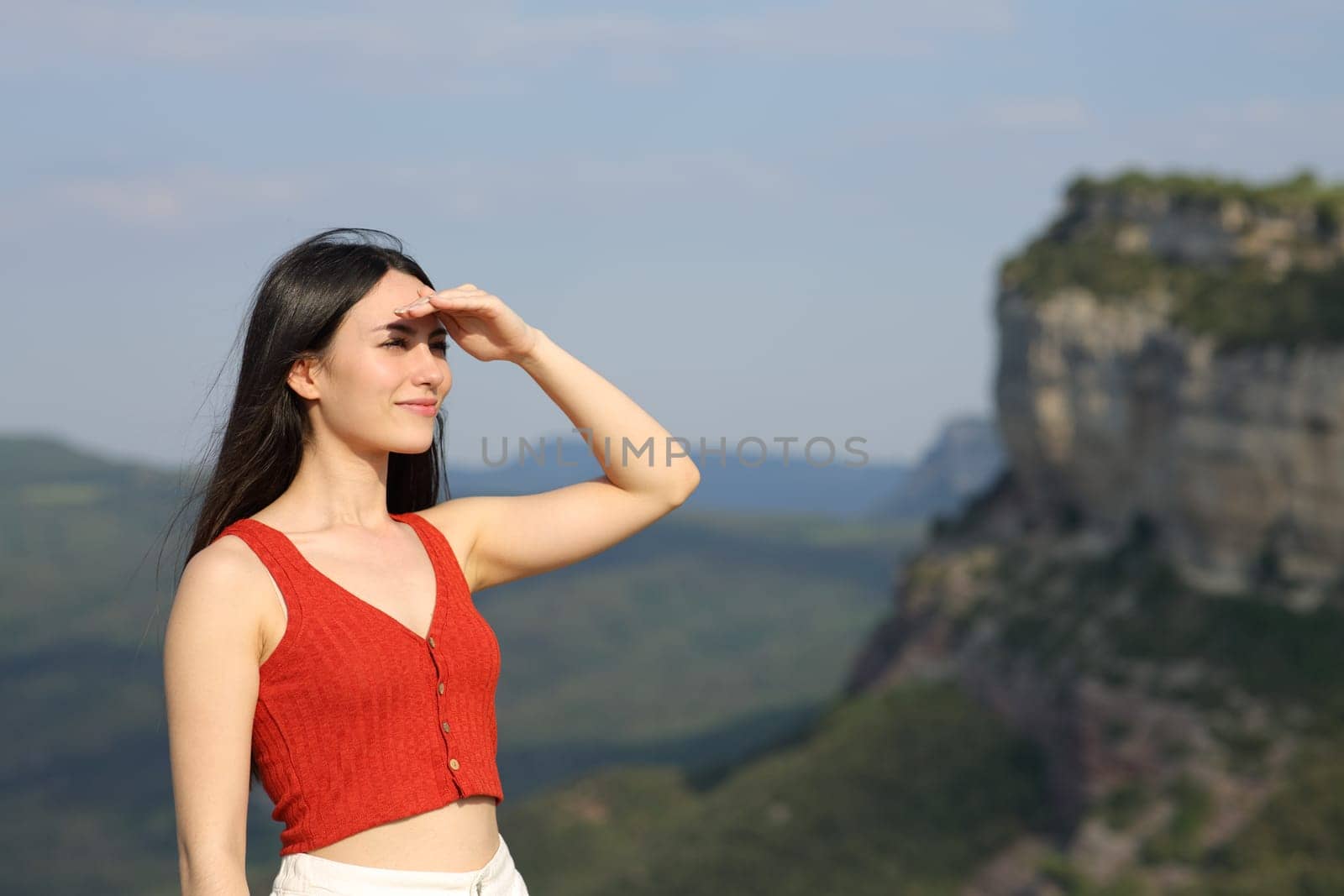 Asian woman looking forward protecting from sun with her hand in the mountain