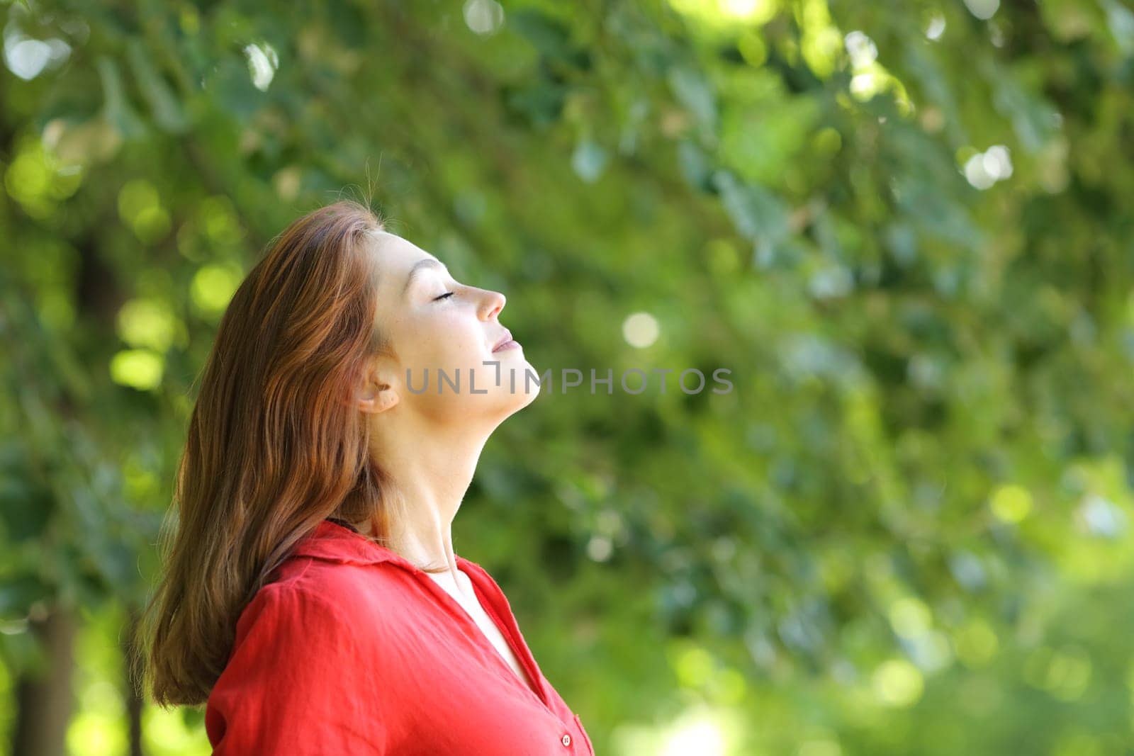 Profile of a woman in red breathing fresh air in a green park