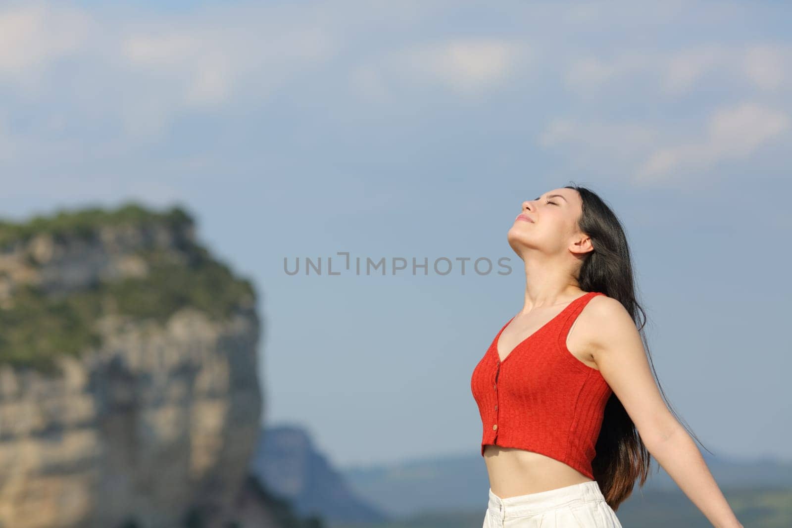 Mixed race woman in red breathing fresh air standing in the mountain