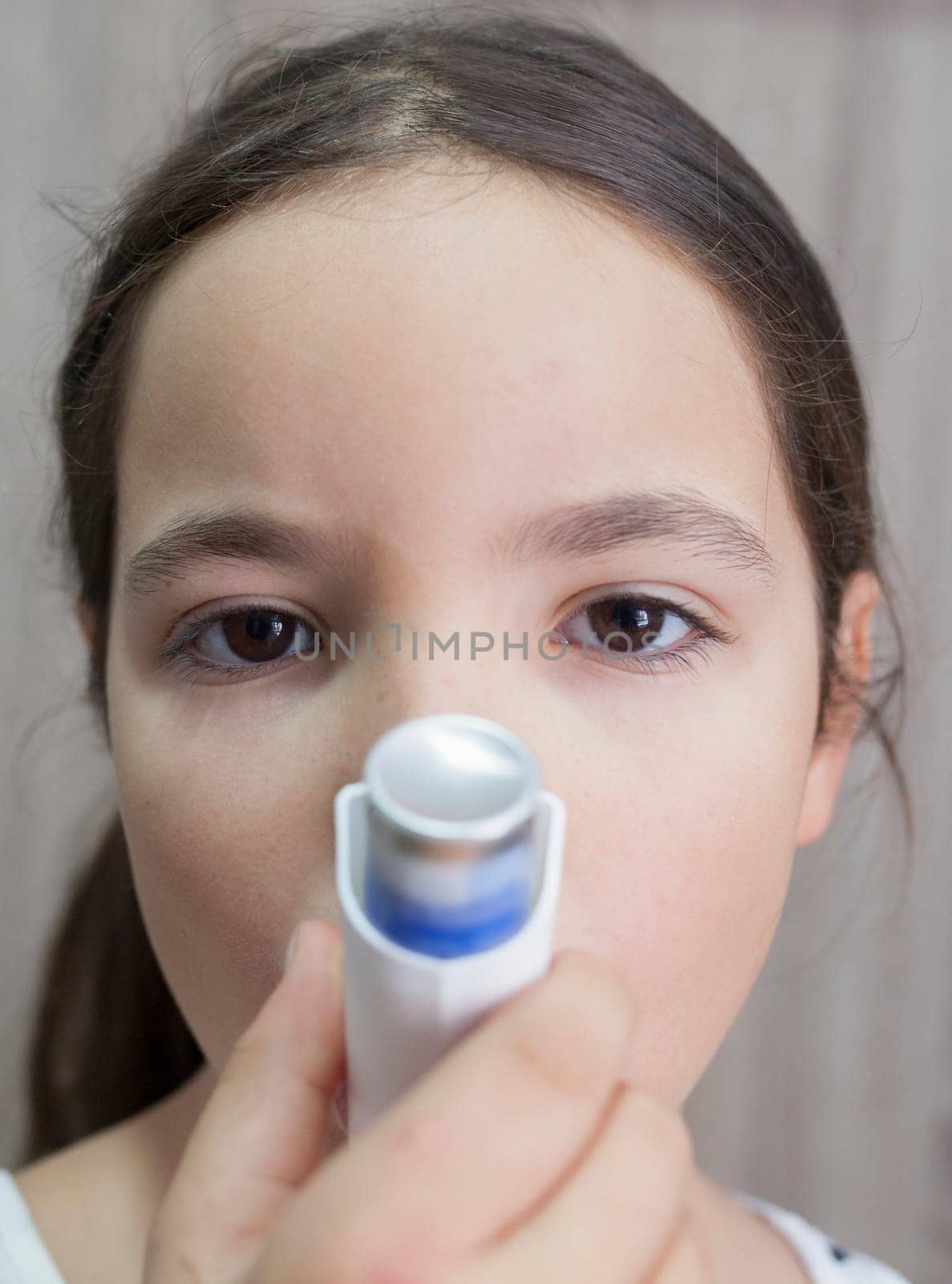 Child girl using medical spray for breath. Inhaler. Front view