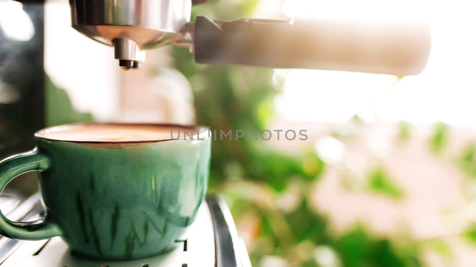 Green cup of coffee on coffee maker machine with dispenser. Mug full of espresso, americano or cappuccino coffee. Blurred background. Morning coffee in the stylish kitchen, cafe or restourant.