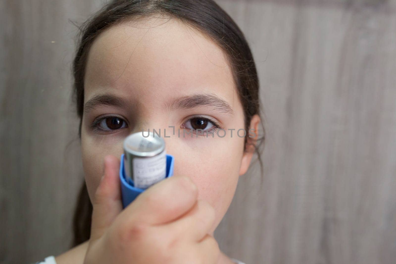 Child girl using medical spray for breath. Inhaler. Front view