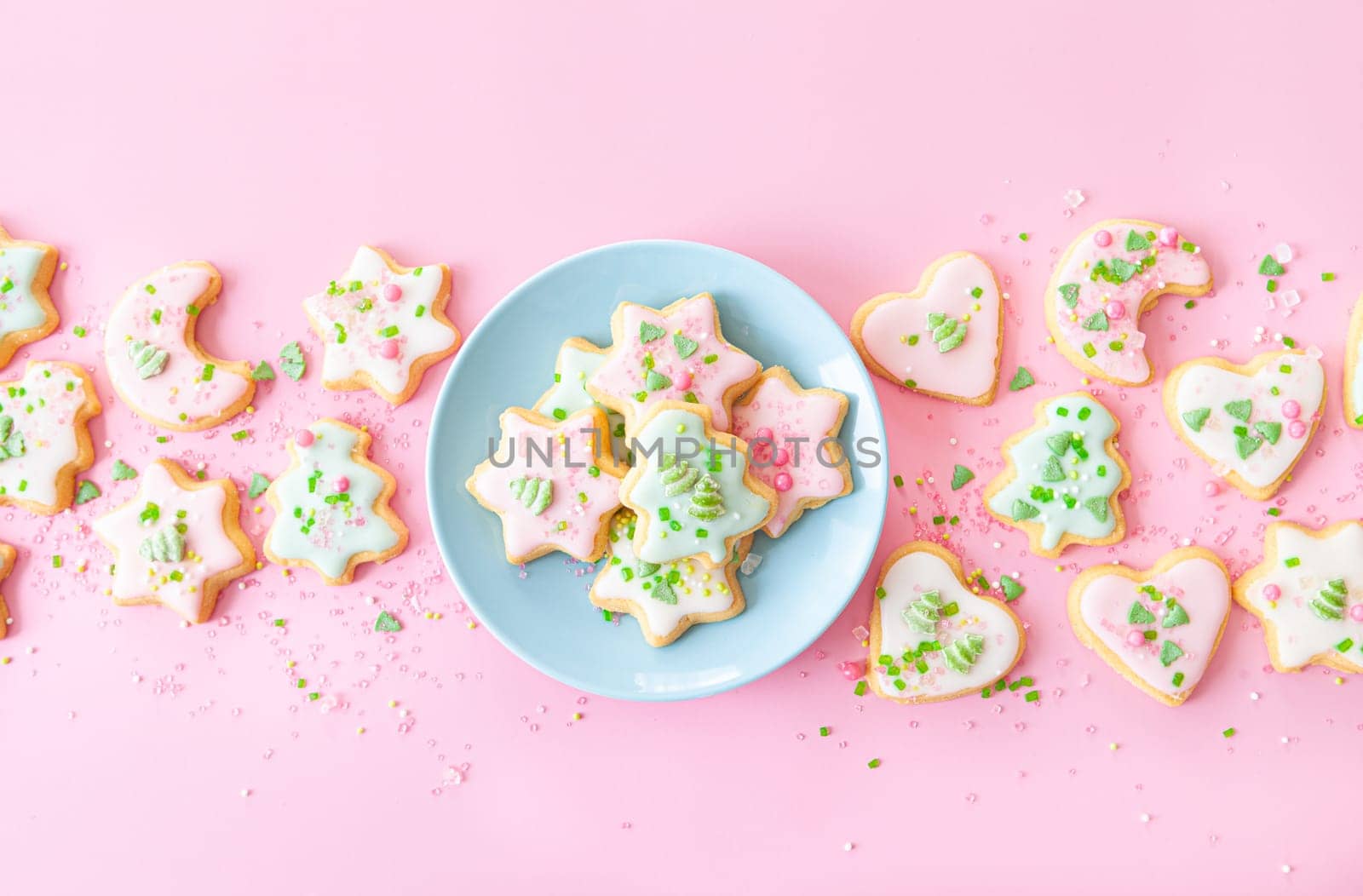 Colorful Christmas cookies with sugar sprinkles on a pink background