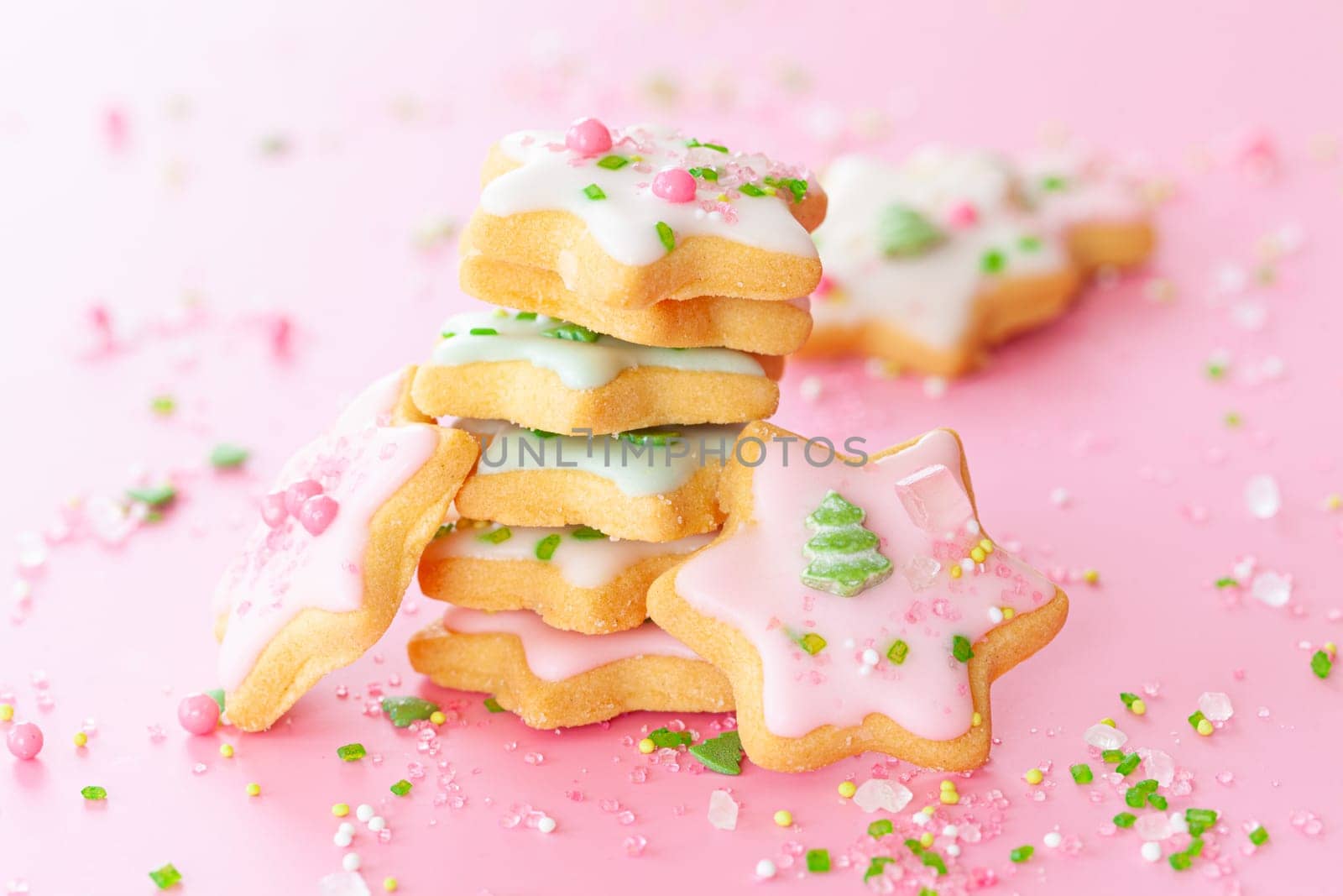 Colorful Christmas cookies with sugar sprinkles on a pink background