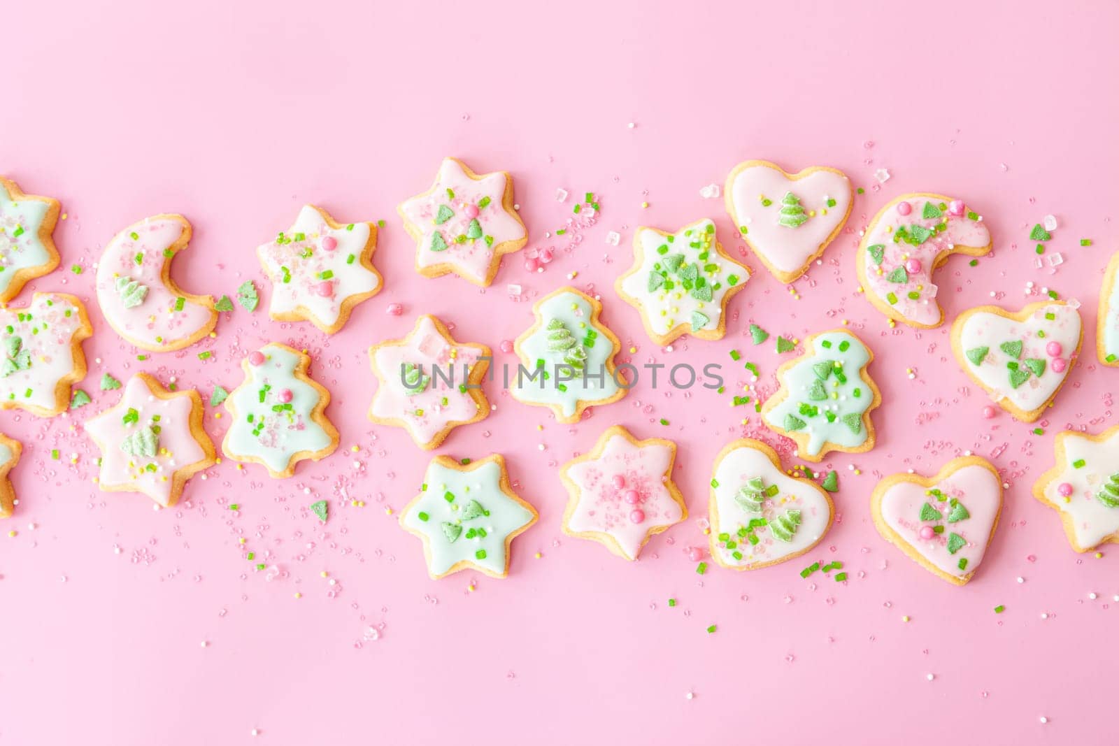 Colorful Christmas cookies with sugar sprinkles on a pink background