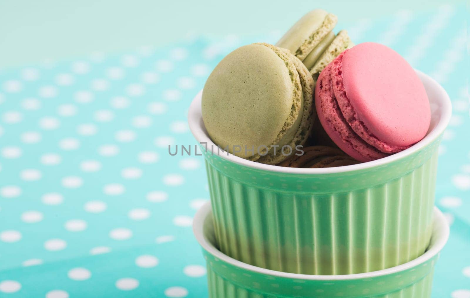 Sweet Macarons with green bowls and green fabric background