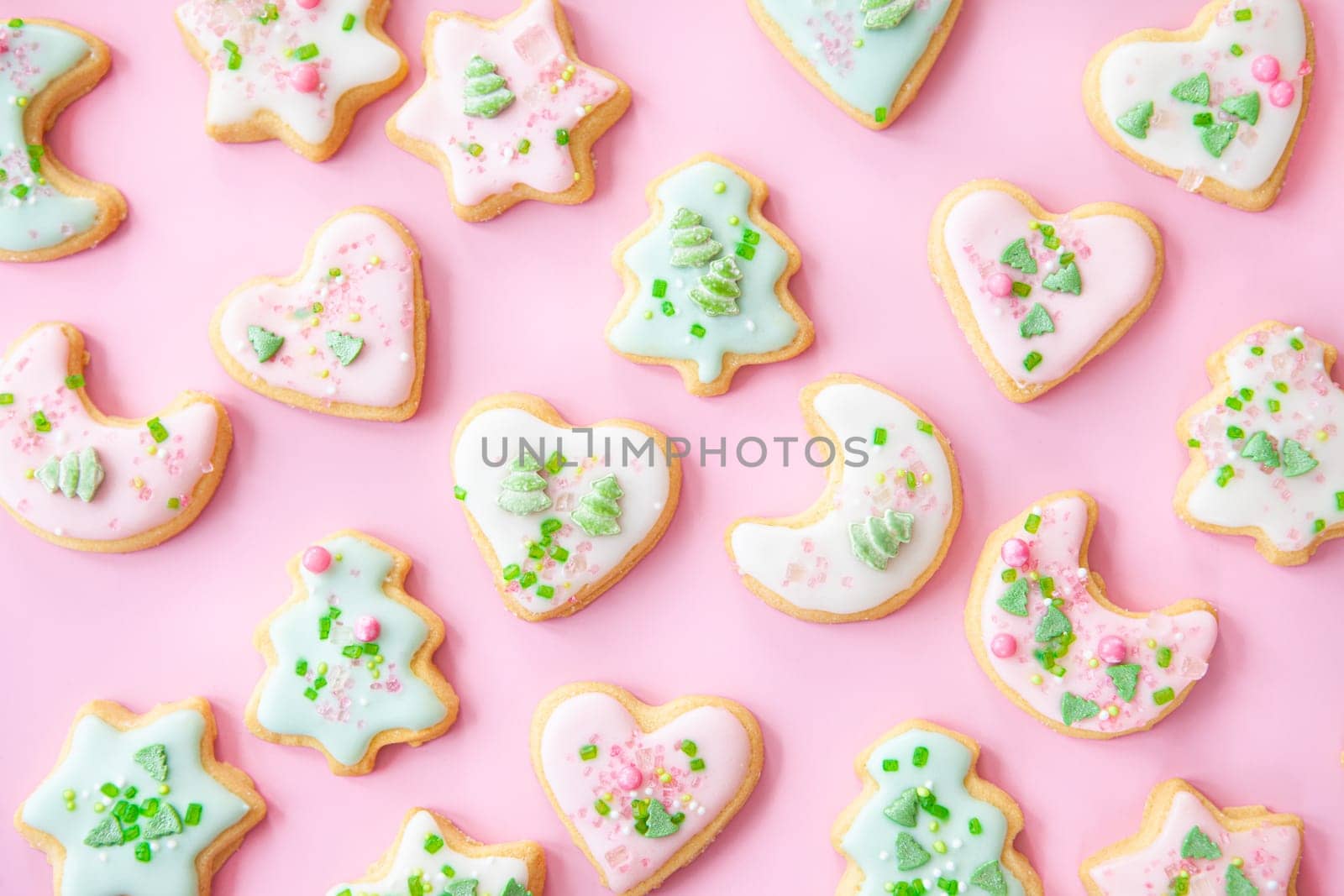 Colorful Christmas cookies with sugar sprinkles on a pink background