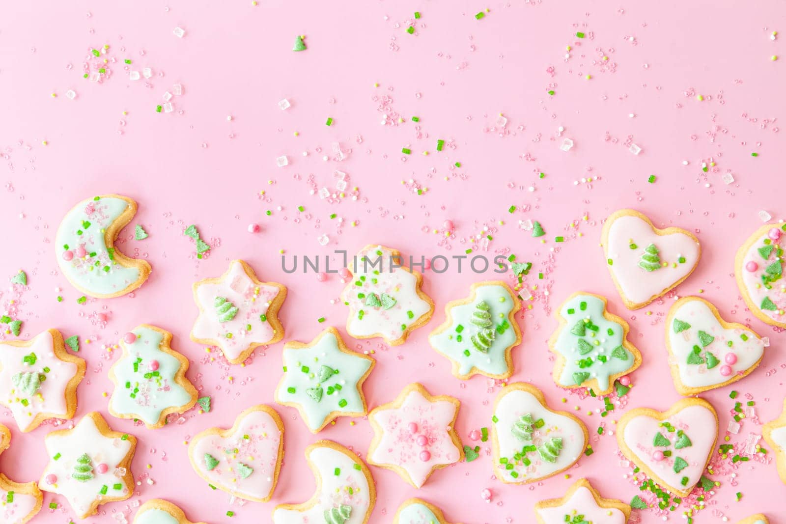 Colorful Christmas cookies with sugar sprinkles on a pink background