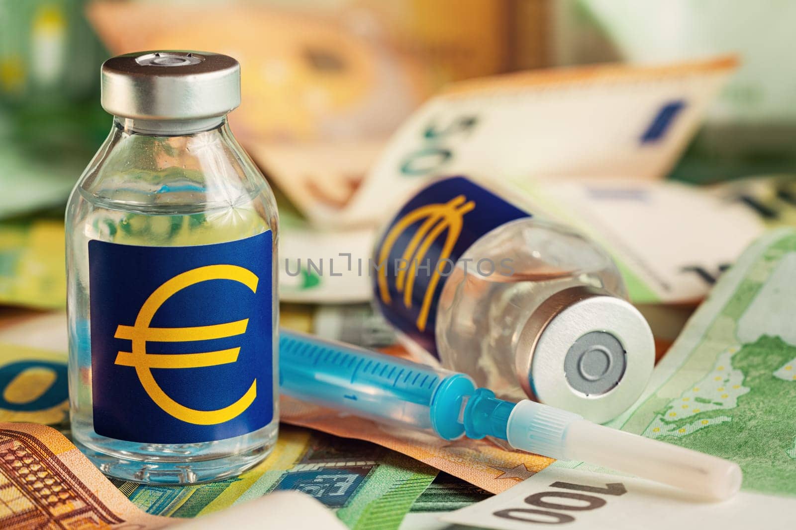 Vaccine price, cost or capital injection concept - glass vial and eur sign on pile of euro bank notes, syringe near, closeup detail.