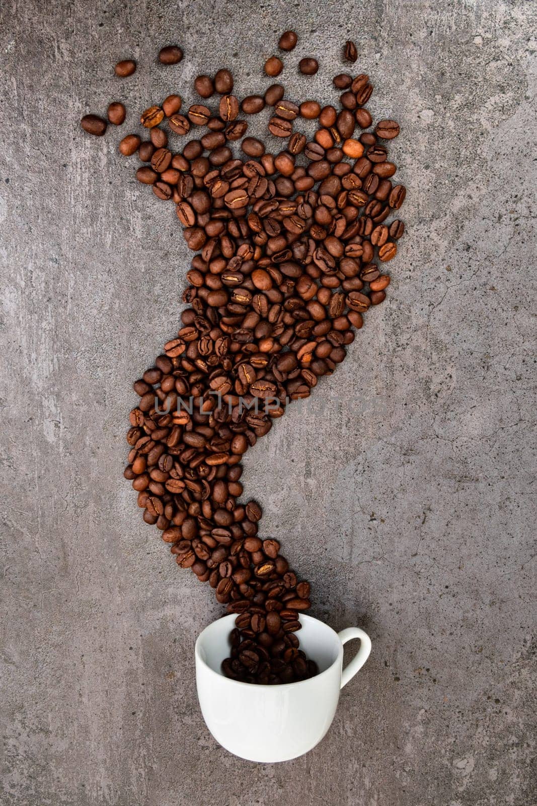 Spilled cup of coffee with roasted  beans forming a smoke shape, vertical