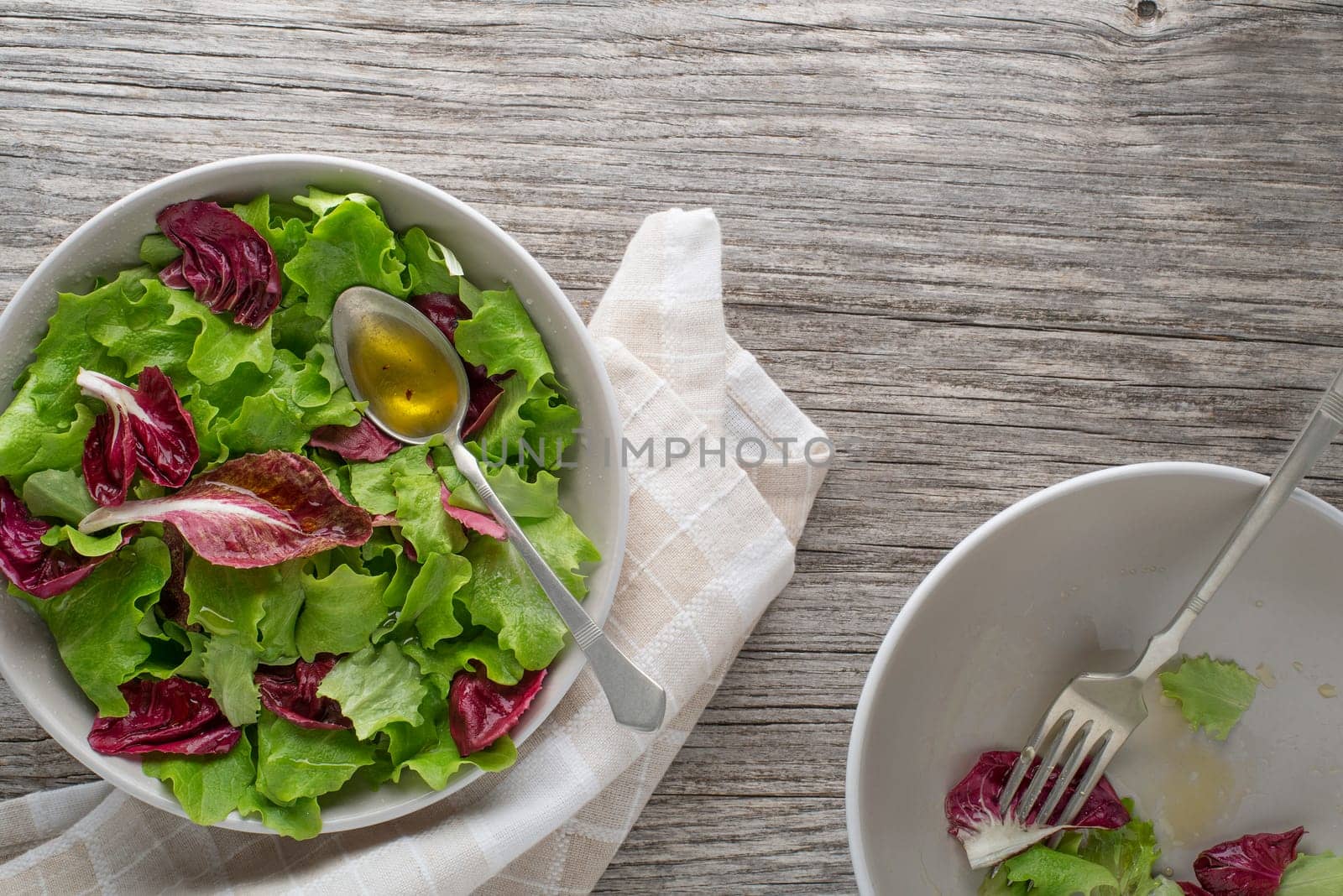 Healthy red and green lettuce salad meals on wooden table background. Eating fresh radicchio and young lettuce with dressing sauce