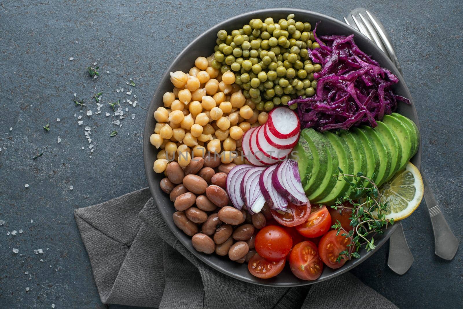 Healthy vegan lunch bowl. Avocado, chickpeas, tomato, red cabbage, green peas, red onion and radish vegetables salad. Healthy balanced vegetarian food concept Top view. Copy space