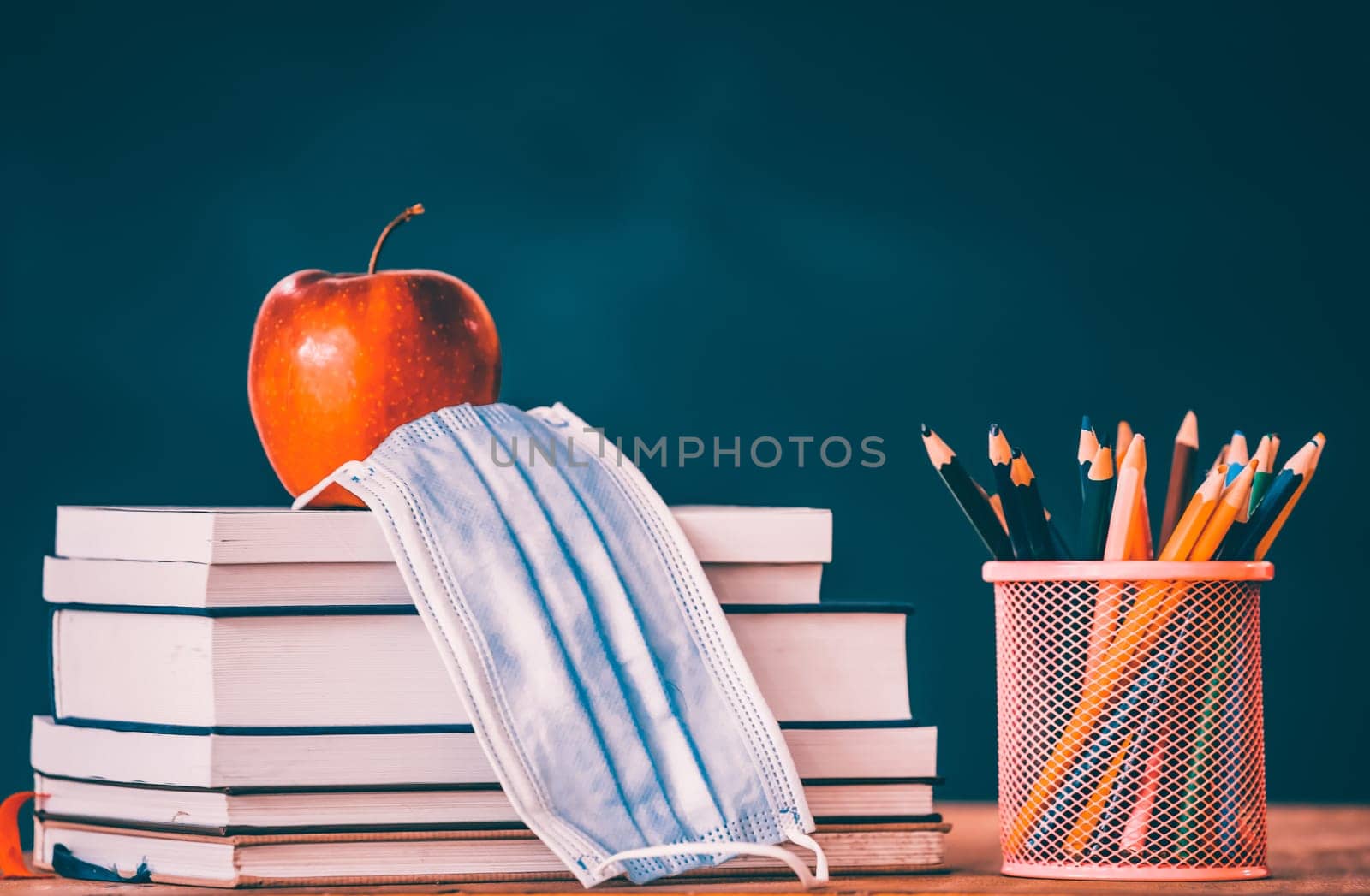 Back to school after coronavirus pandemic. School stationery supplies, medical masks over blackboard background.Concept of learning, maintaining social distance.