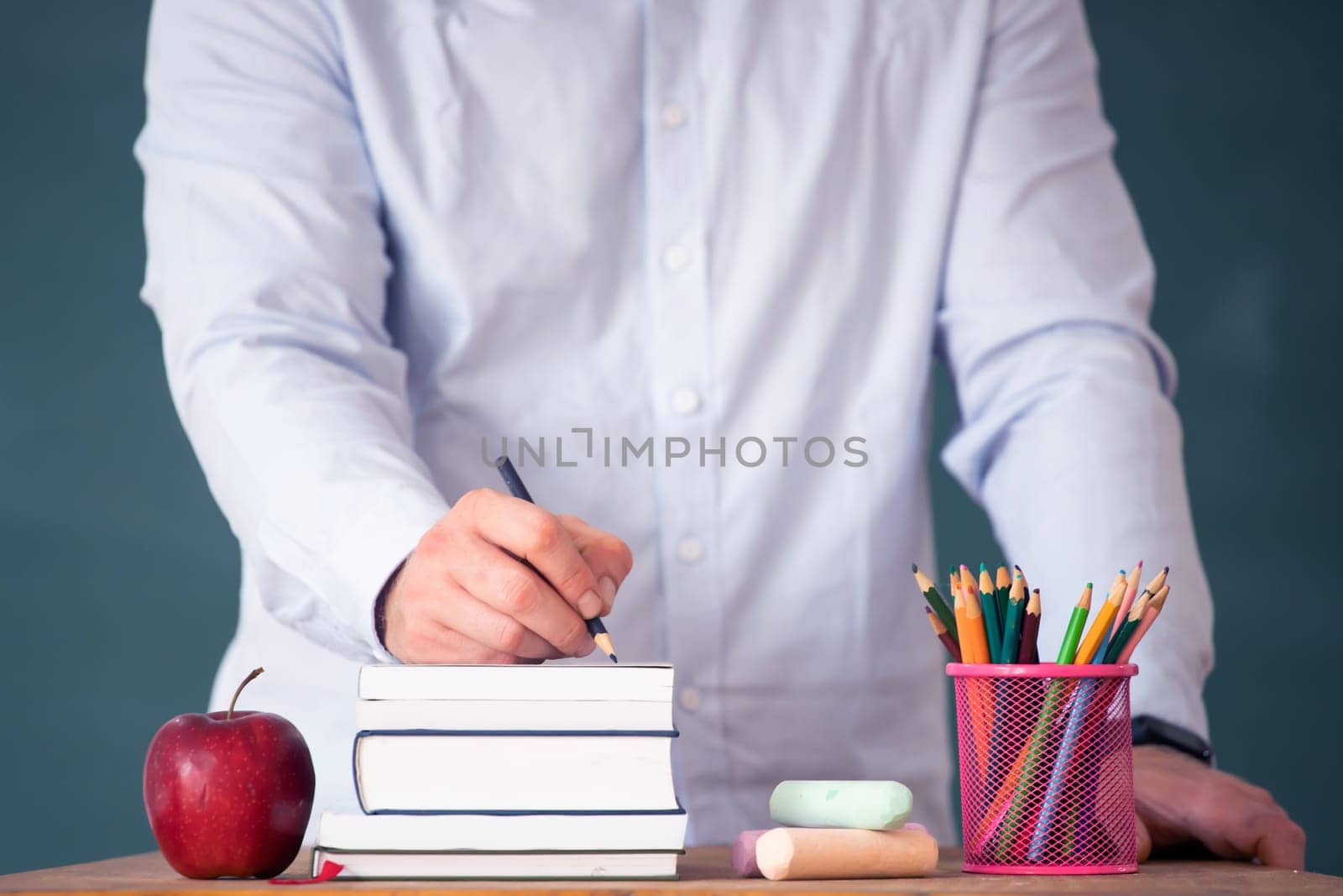 Back to school concept: teacher giving books to her studens in the classroom at the begining of the new school season.