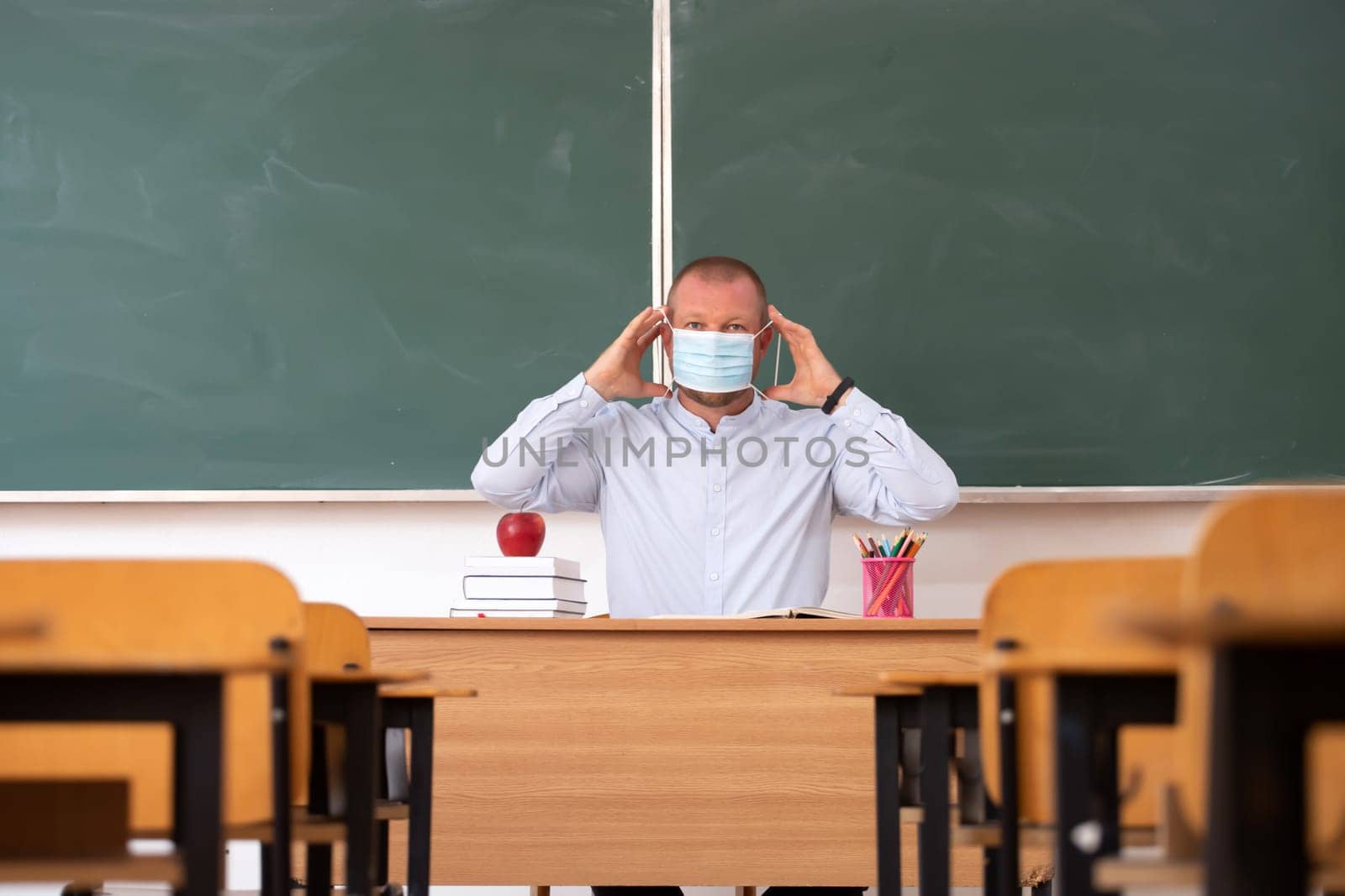 Teacher with mask teaching how to wear mask at school. Social distanting and classroom safety during coronavirus epidemic