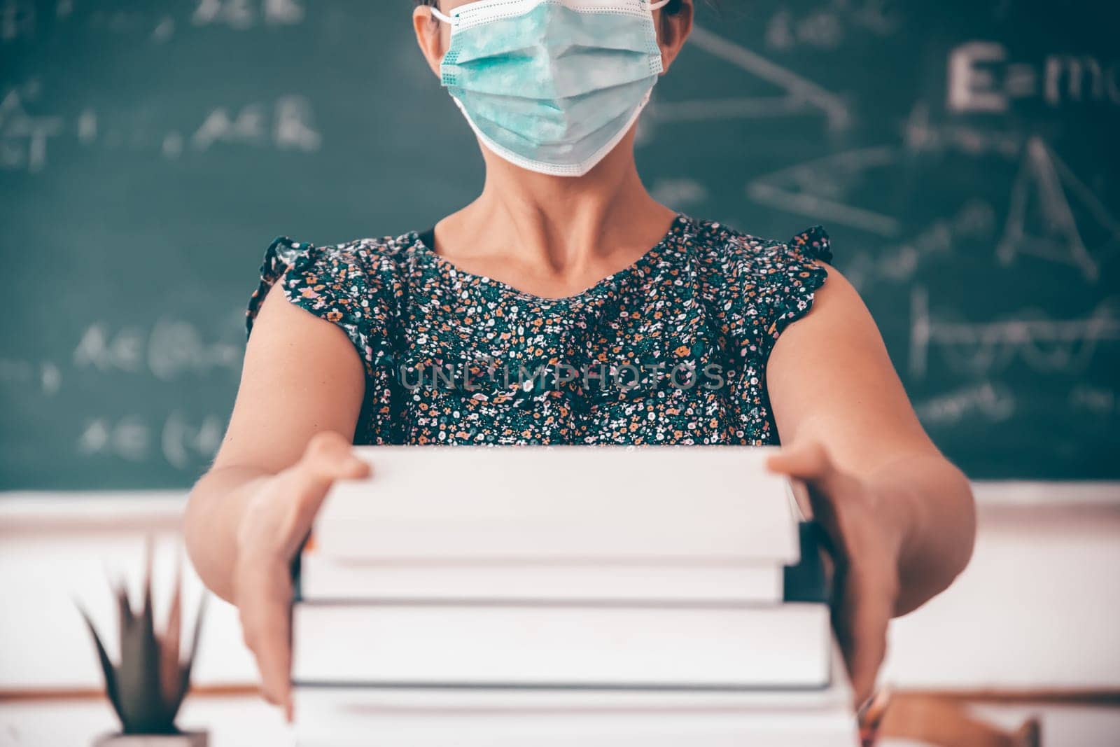 Teacher with face mask welcoming children back at school after lockdown. Back to school during COVID-19 pandemic.