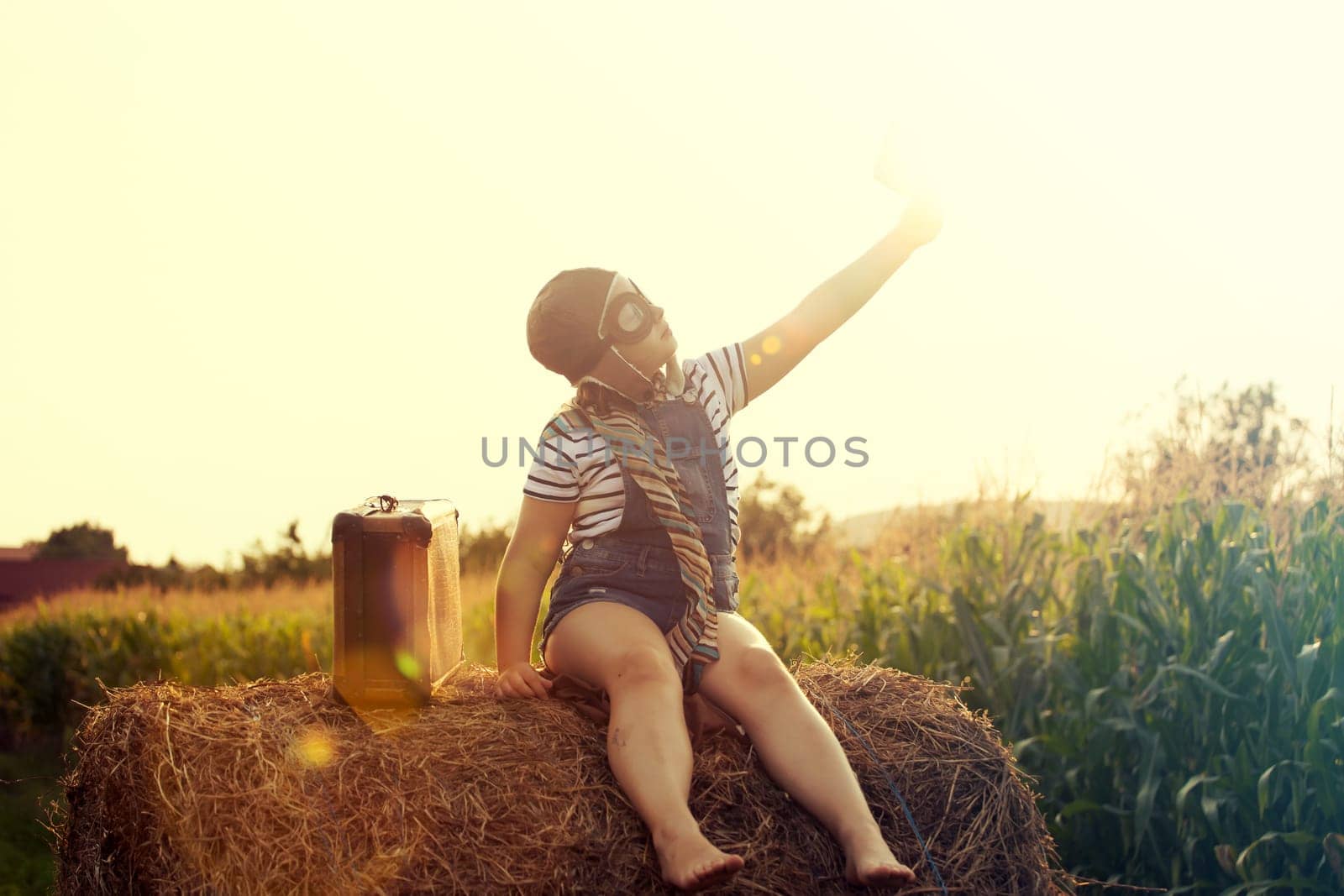 Happy kid playing in pilot helmet pretend to be aviator. Travel, vacation and freedom concept. Childhood, imagination, dream.