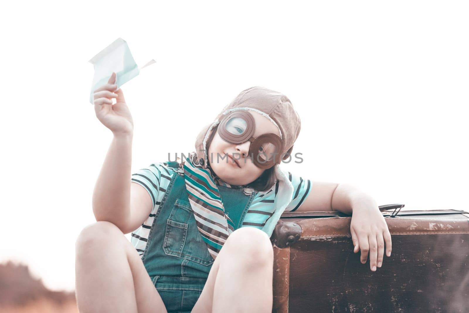 Happy kid playing in pilot helmet pretend to be aviator. Travel, vacation and freedom concept. Childhood, imagination, dream.