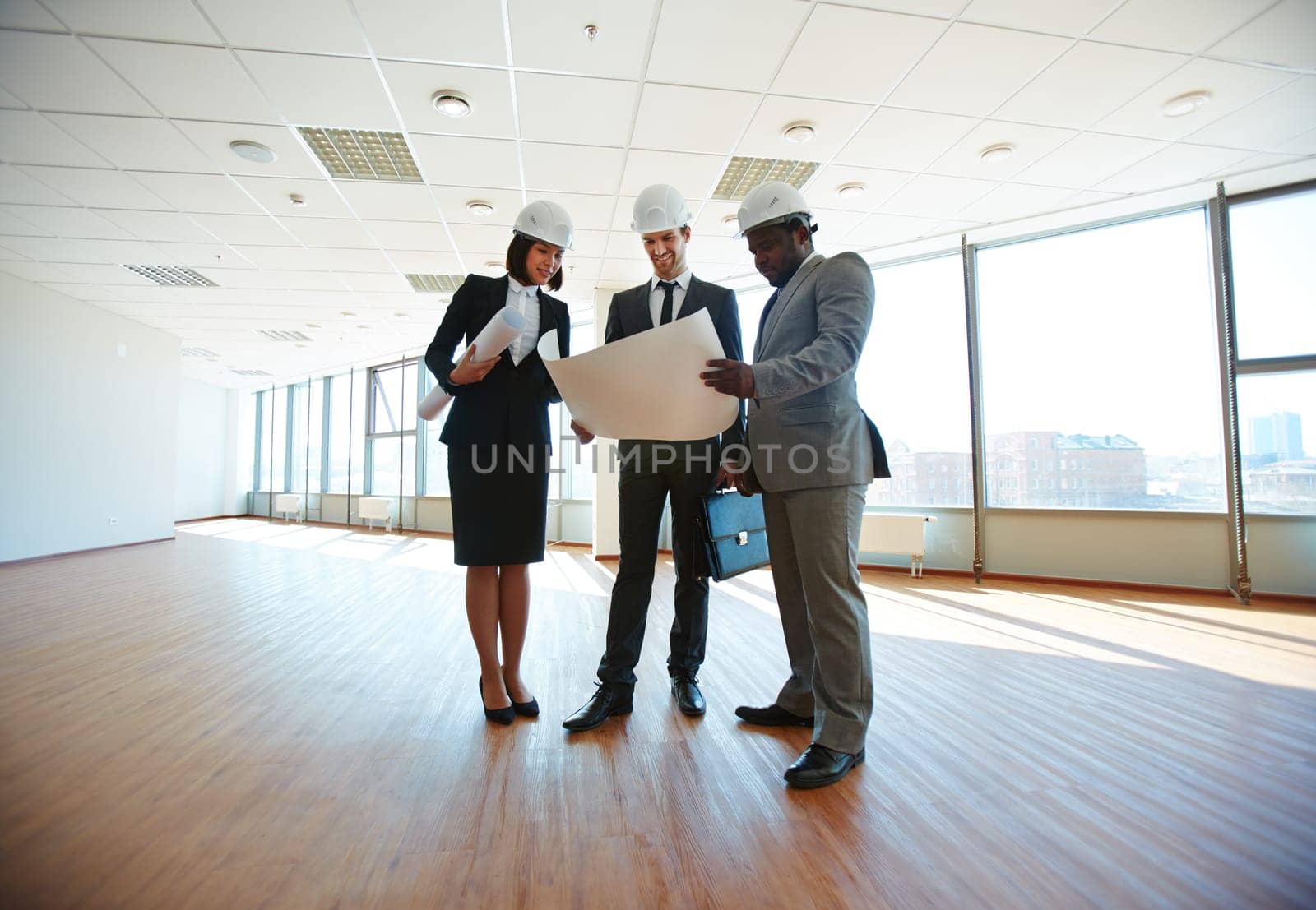 Group of architects discussing blueprint in office