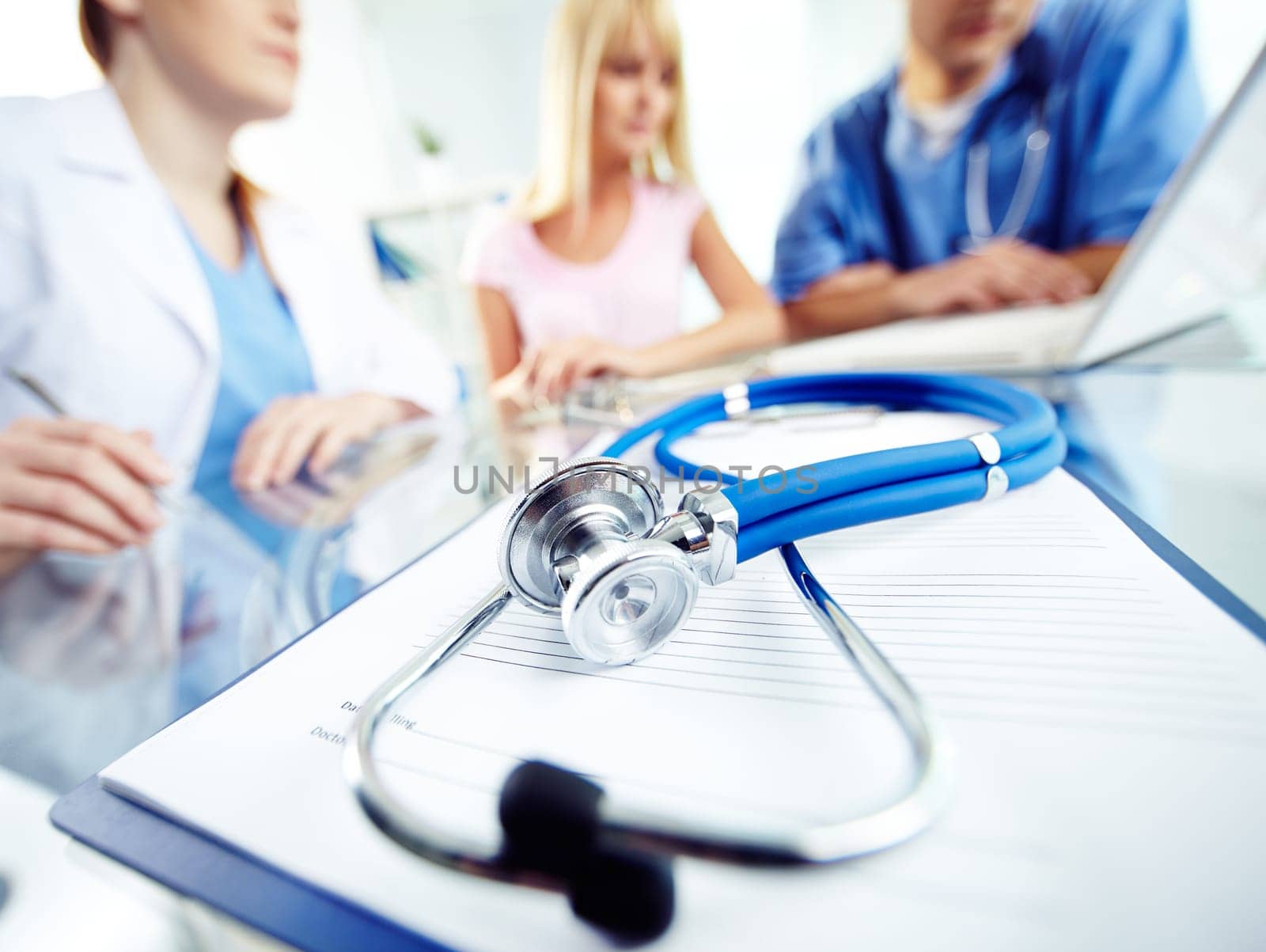 Prescription form and stethoscope on background of working practitioners