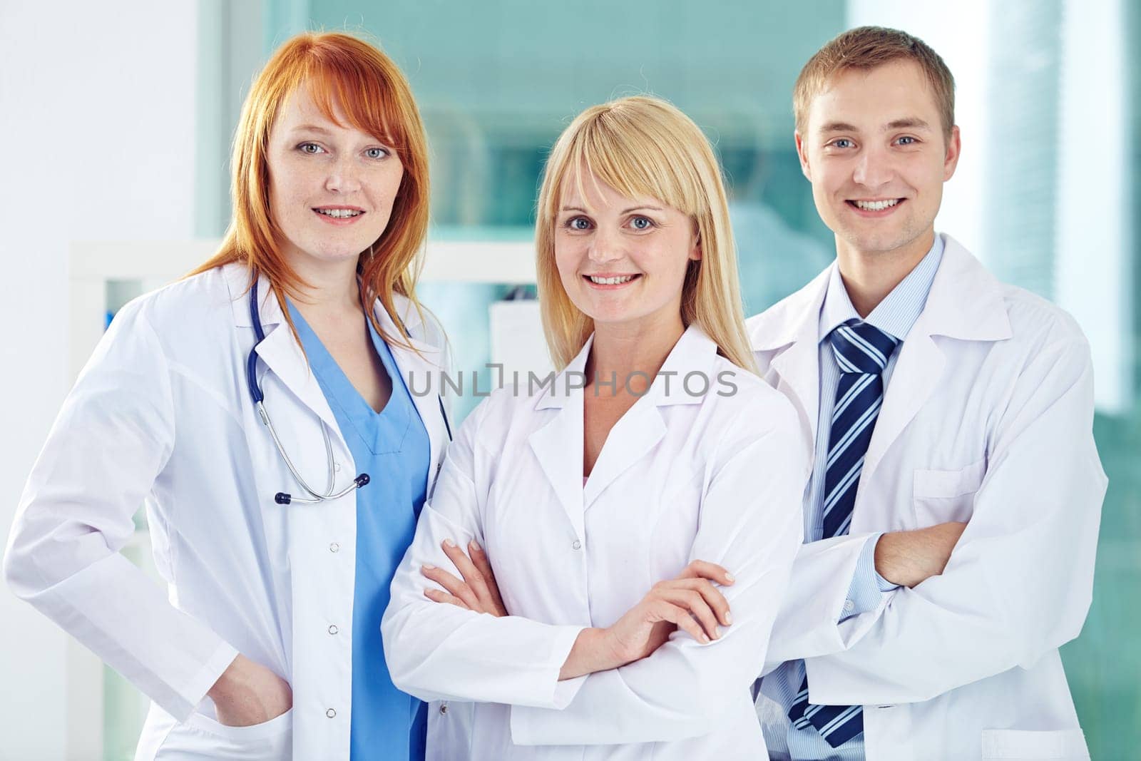 Happy young colleagues in white coats looking at camera