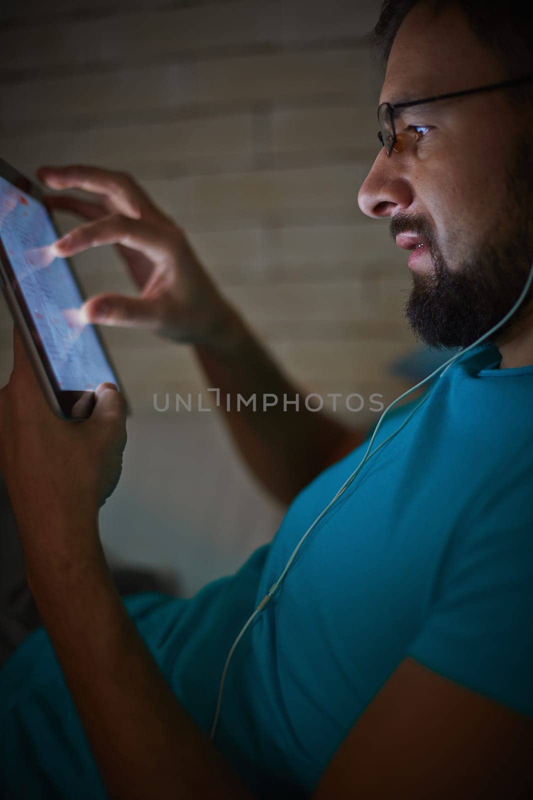 Handsome young man with earphones using touchpad at night