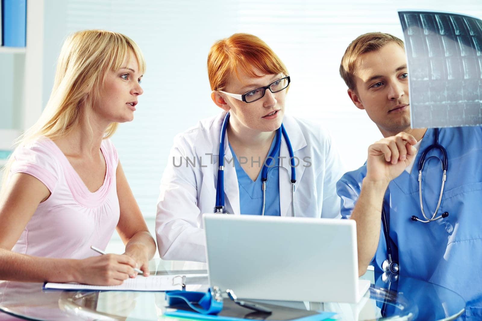 Portrait of young doctor commenting x-ray to his colleagues