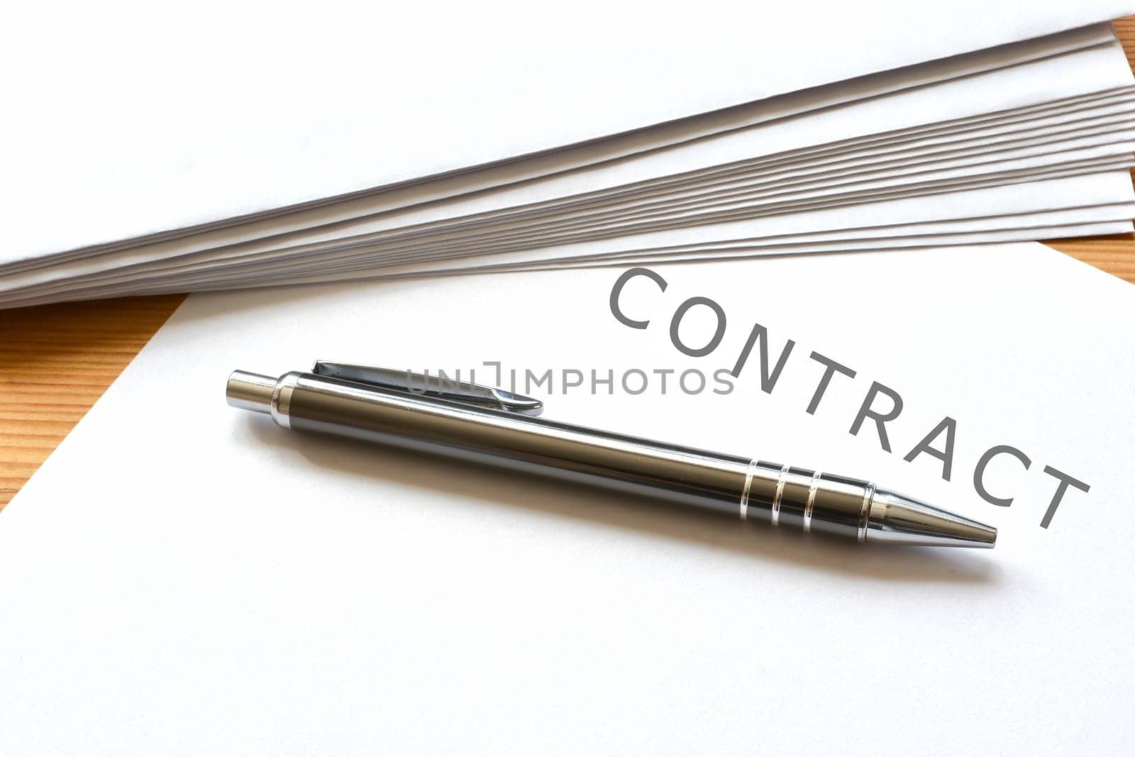 a contract and a ballpoint pen are on a desk