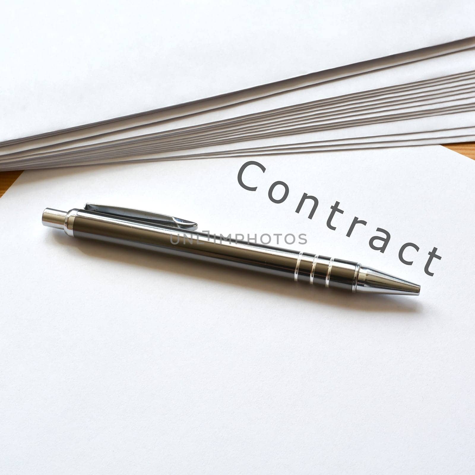 a contract and a ballpoint pen are on a desk