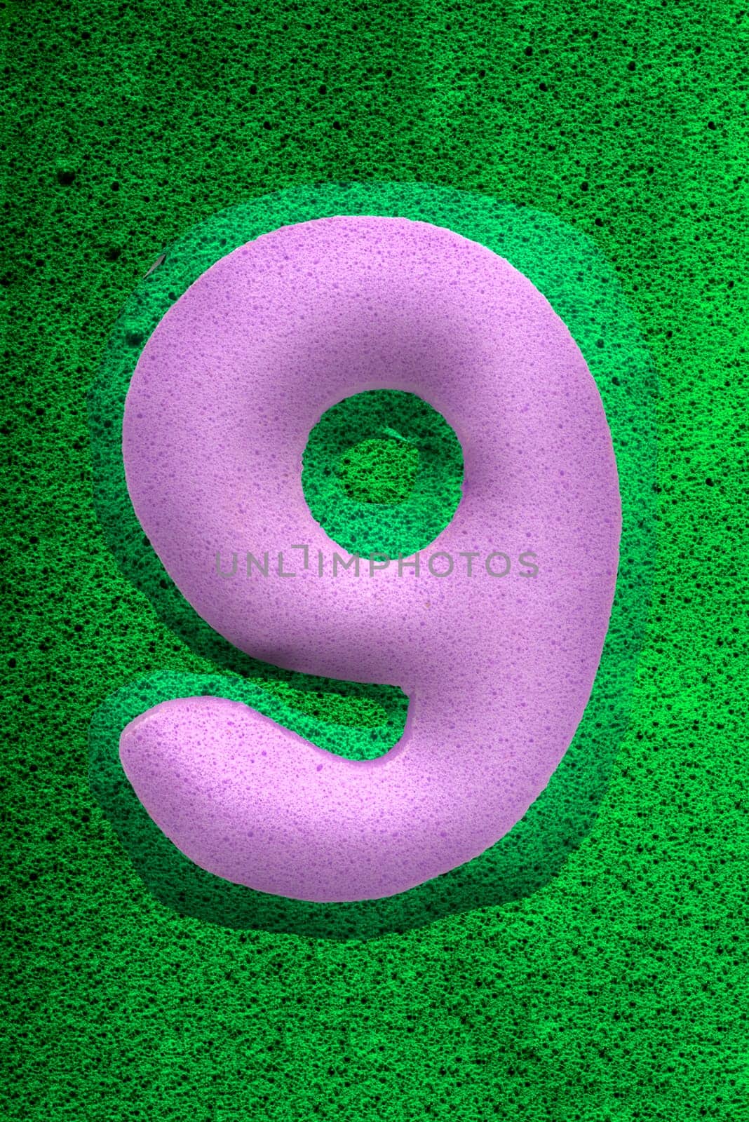 The number nine in a purple  sponge like texture, raised 3D from the green background.