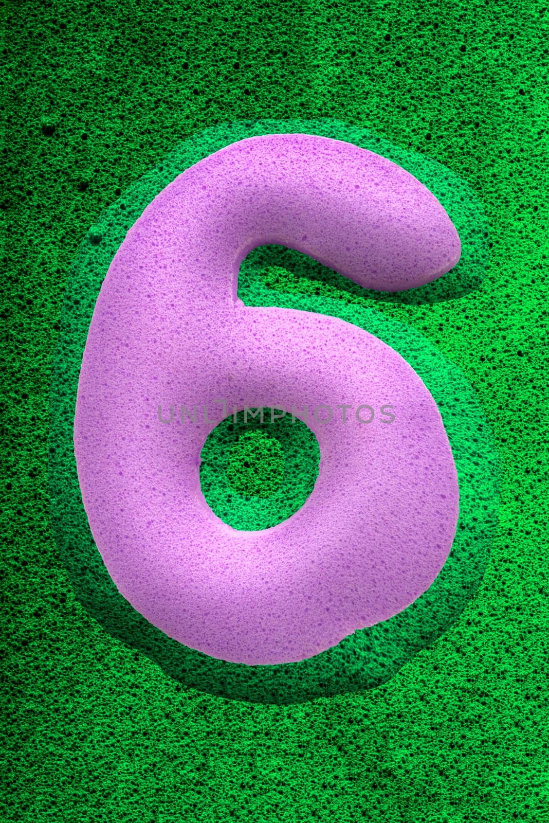 The number six in a purplesponge like texture, raised 3D from the green background.