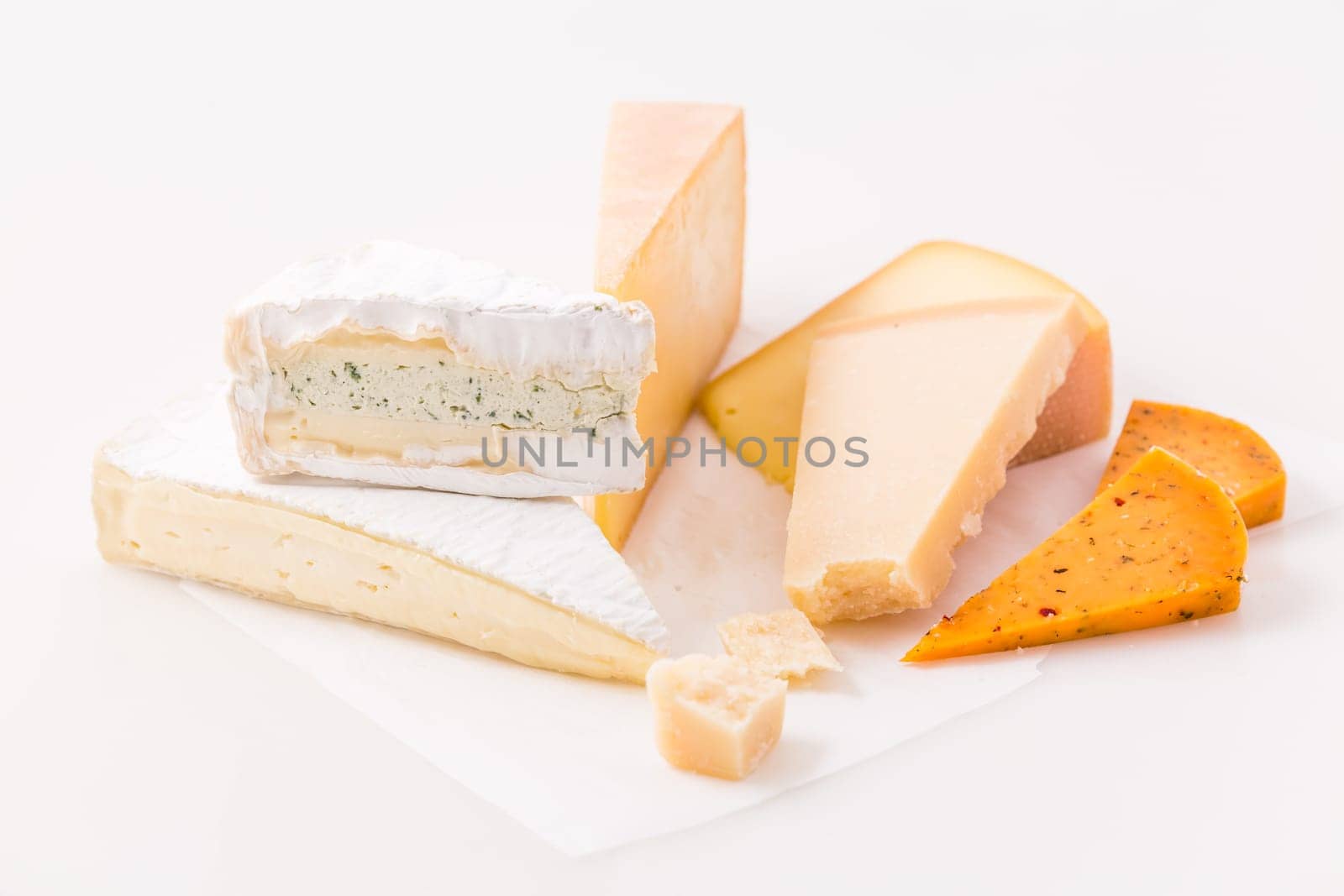 Assortment of different cheeses on white background. Hard cheese, parmesan, brie and chili cheese.