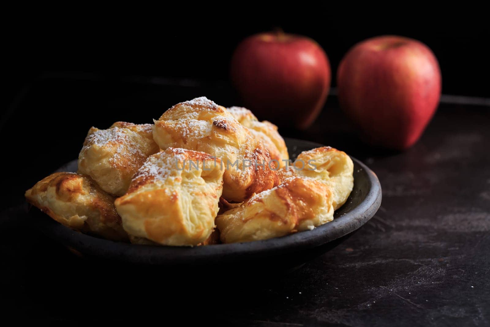 Homemade small apple turnovers in bowl on black background