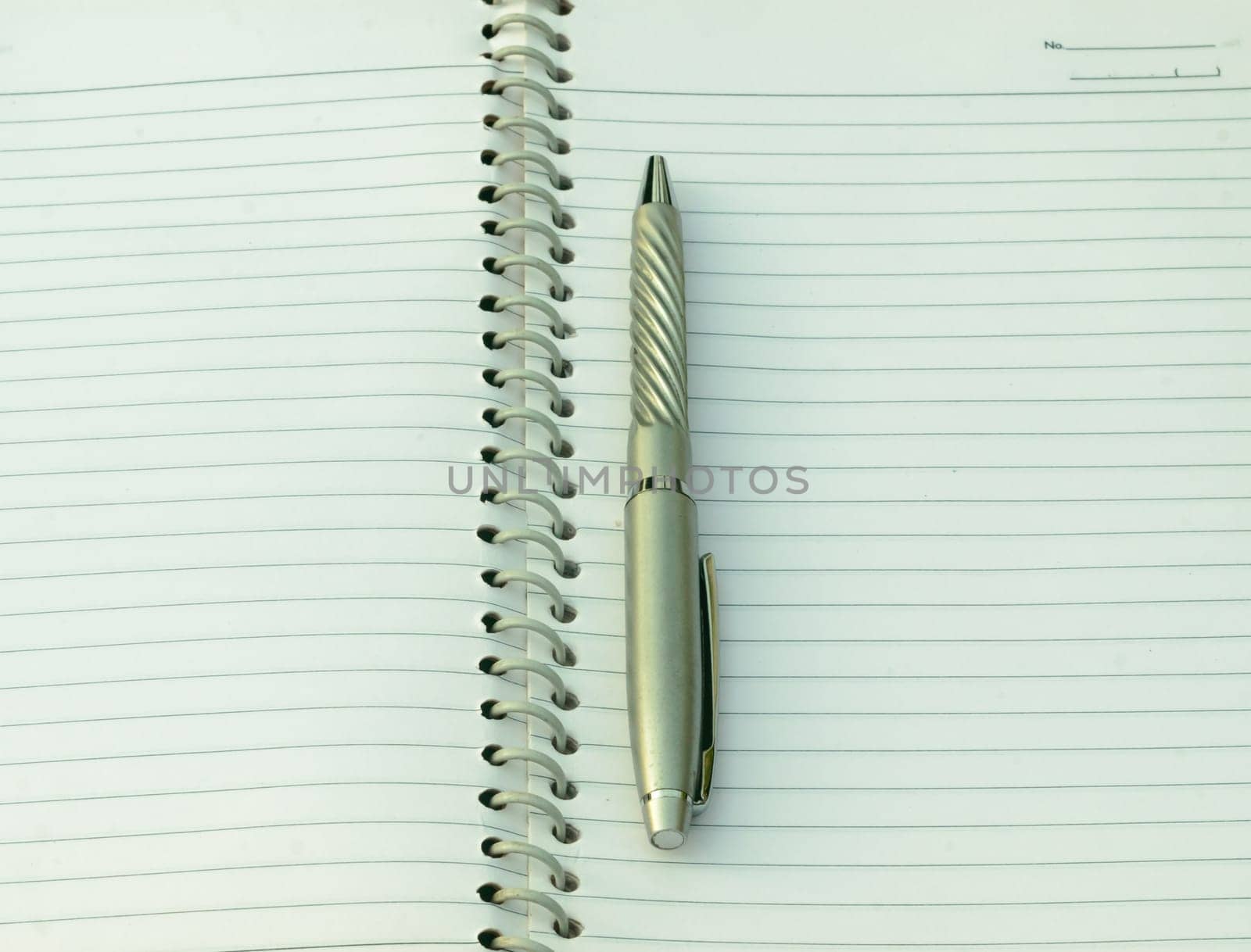 Close up of pen placed on spiral notebook. Full frame shot. High angle view. Business education background.
