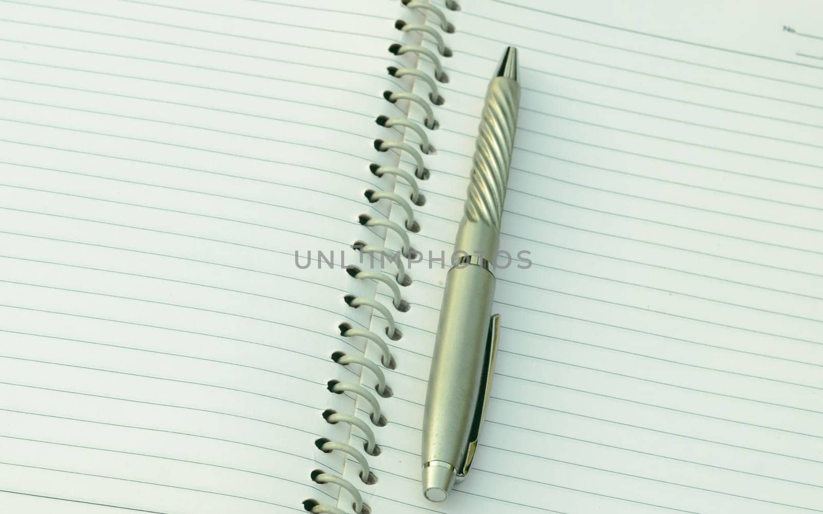 Close up of pen placed on spiral notebook. Full frame shot. High angle view. Business education background.