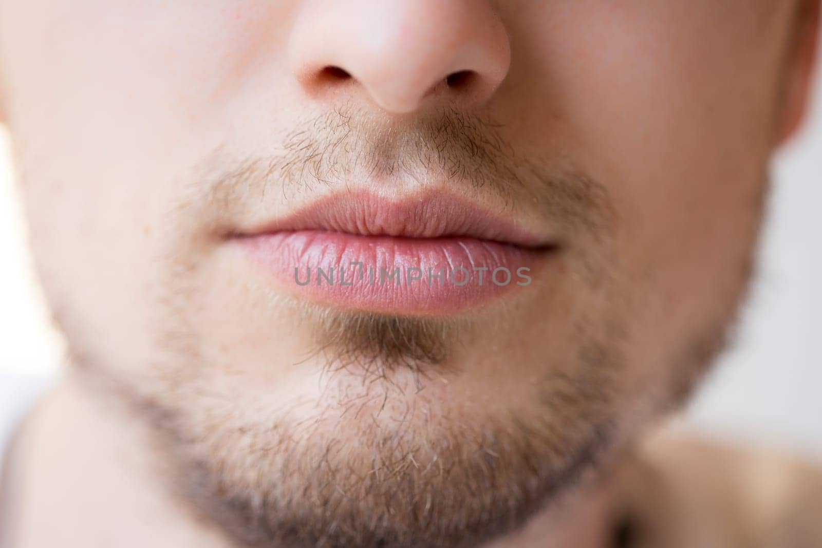 Cloesup of the mouth of a young man: red lips, beard