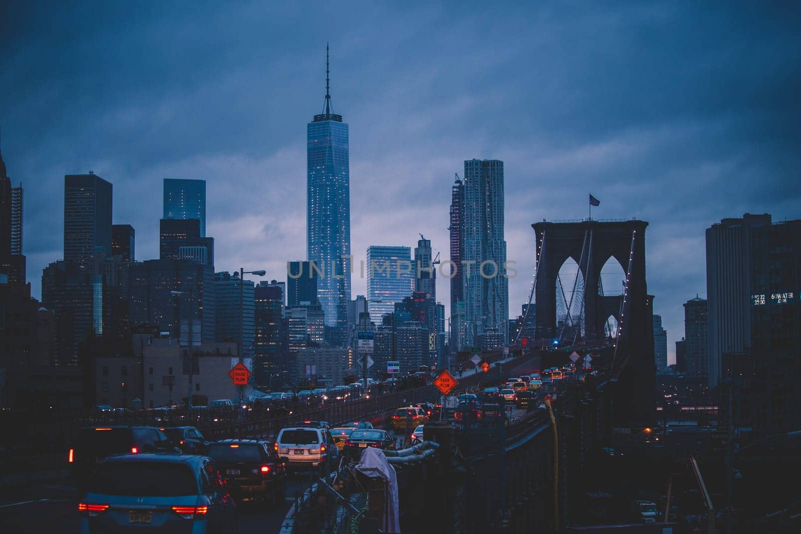 Traffic on Brooklyn bridge and New York City Manhattan downtown skyline at dusk with skyscrapers over East River panorama.