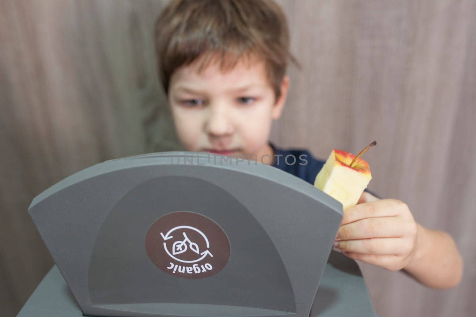 Child boy throwing apple core to waste bin for organic at home. Education about Waste Segregation concept