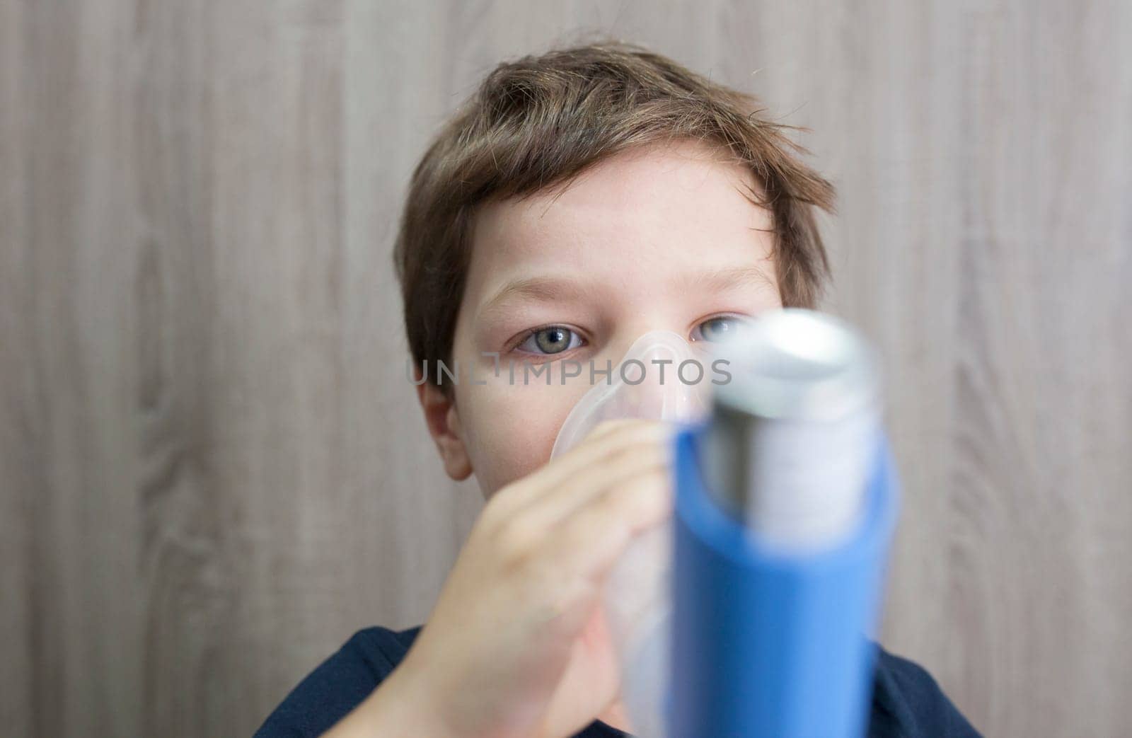 Child boy using medical spray for breath. Inhaler, spacer and mask. Front view