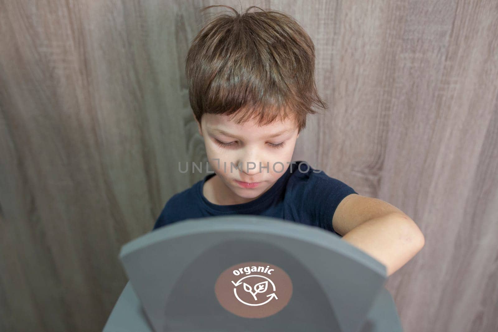 Child boy throwing prganic item to waste bin for orgnic at home. Education about waste segregation concept