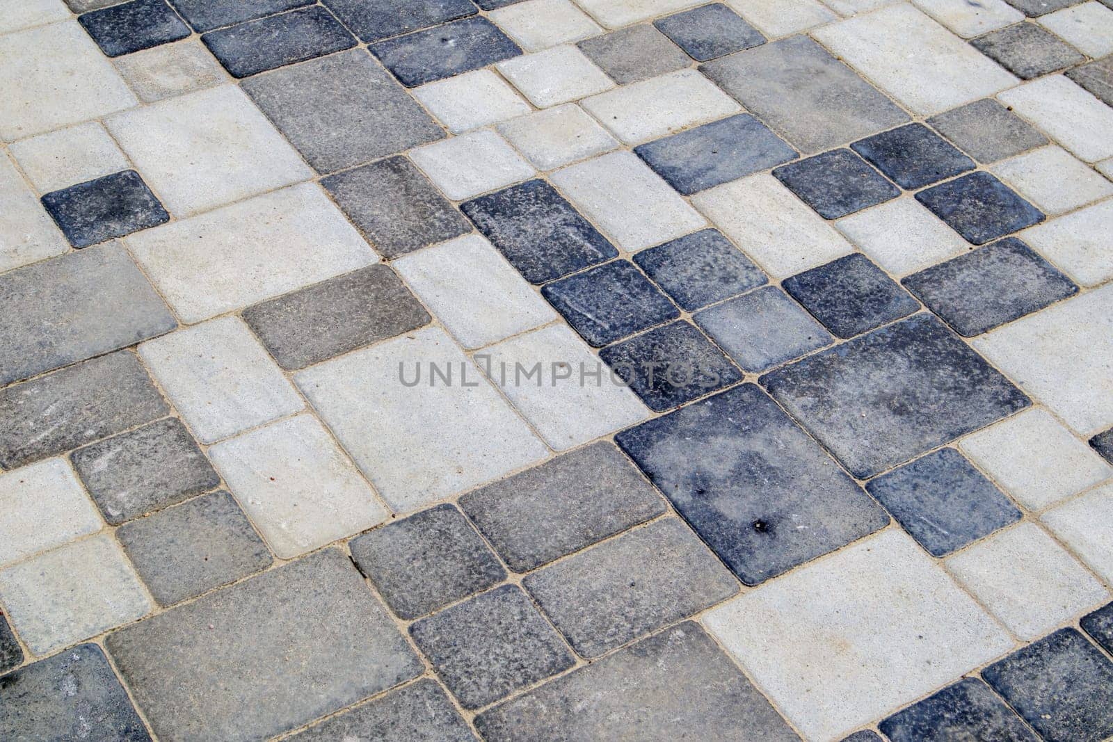 Concrete or paved newly laid gray paving slabs or stones for floors or walkways. Concrete paving slabs in the backyard or road paving. Garden brick path in the courtyard on a sandy foundation