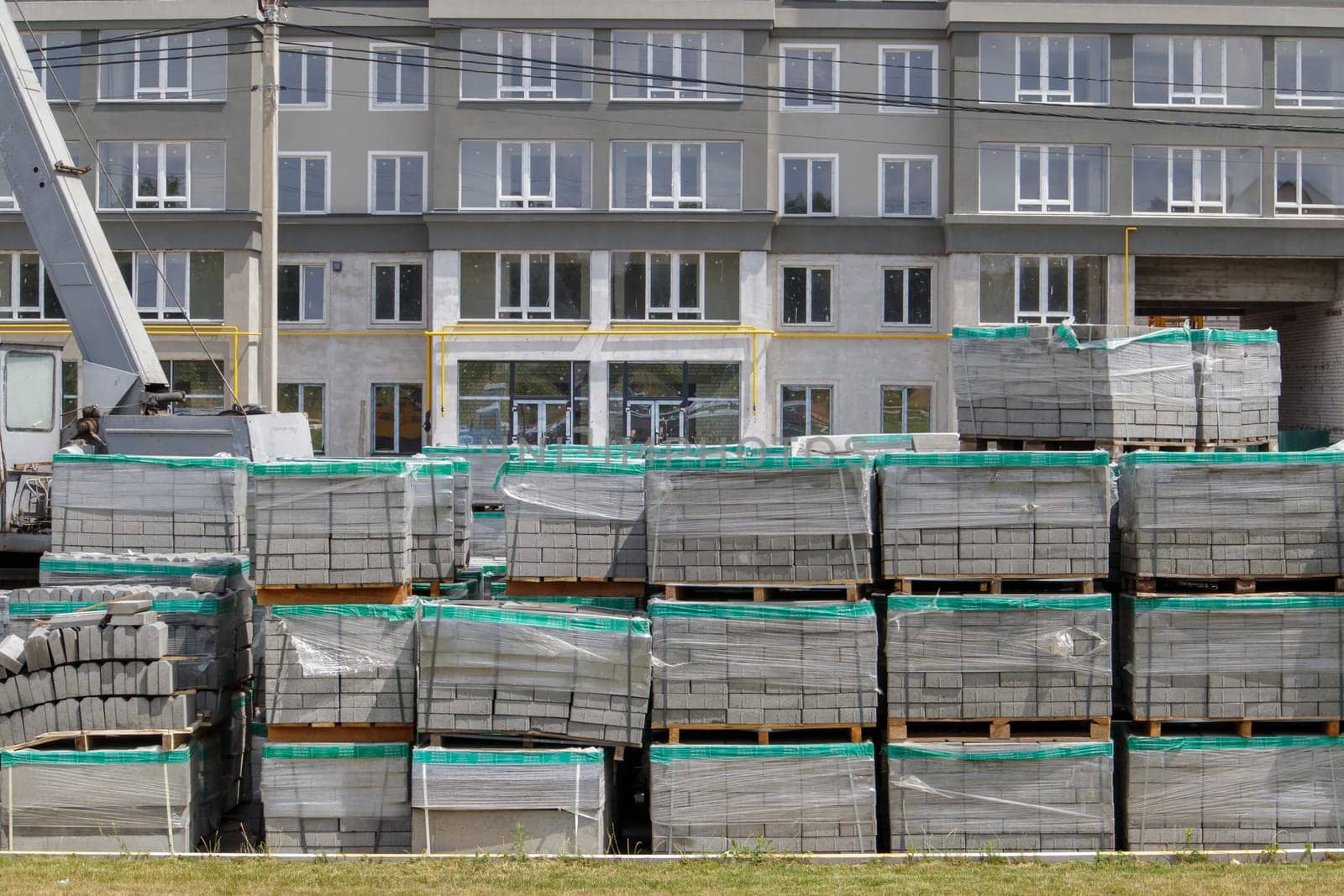 There are a lot of new gray paving slabs on the construction site on plastic-covered pallets. Paving of pedestrian paths on a city street. Ukraine, Kiev - August 19, 2021
