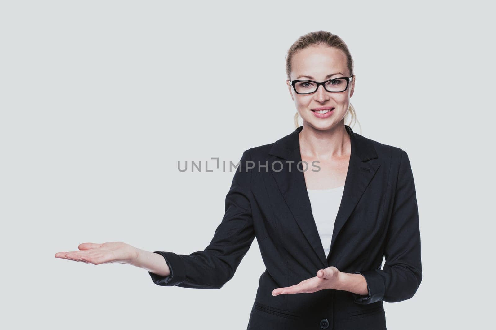 Beautiful young businesswoman smiling, holding open palm with empty copy space. Business woman showing hand sign to side, concept of advertisement product. White background.