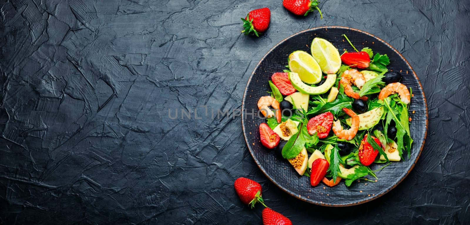 Salad with shrimps,strawberries,avocado and herbs.Seafood salad on rustic wooden background.Copy space,space for text