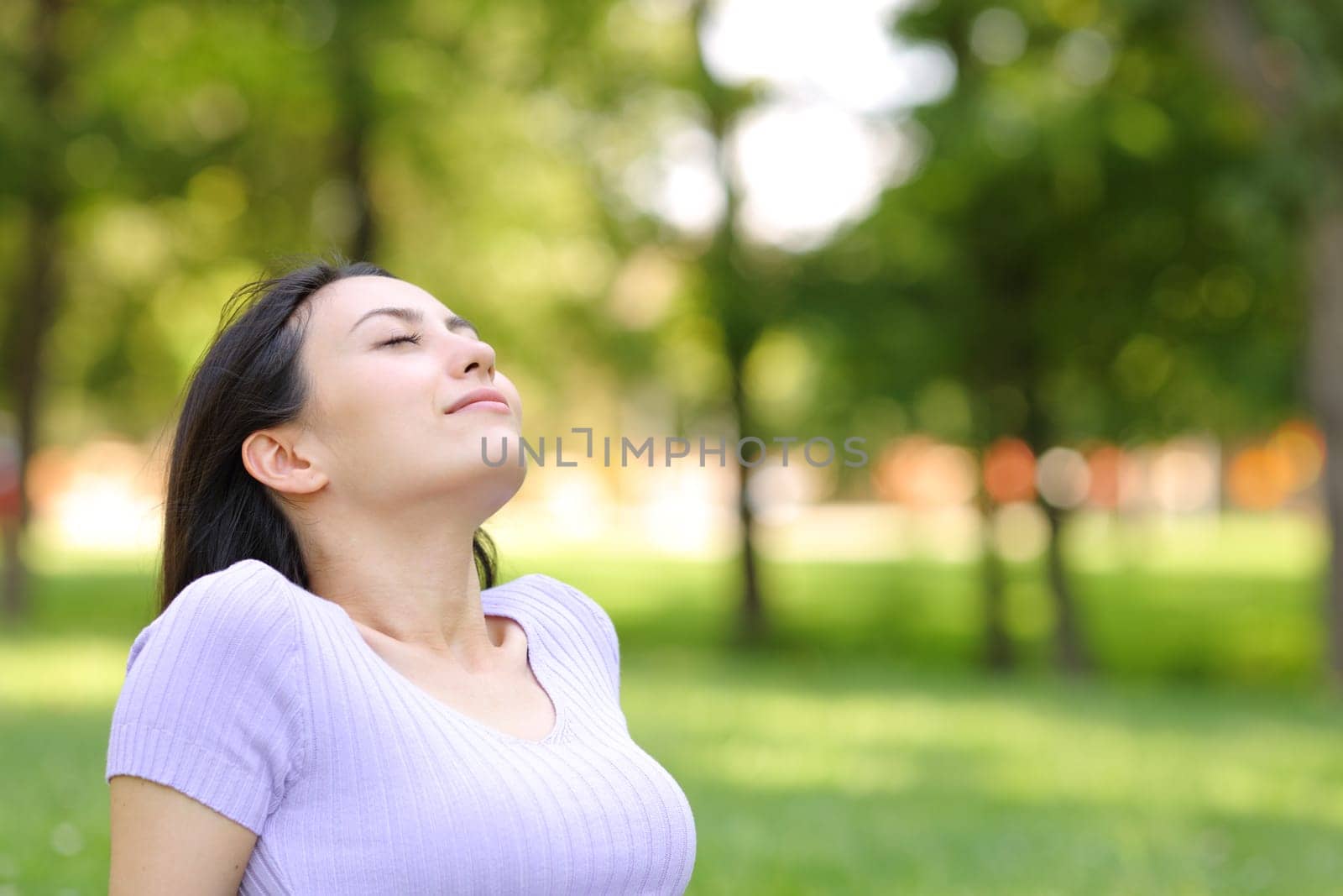 Asian woman breathing fresh air sitting in a park