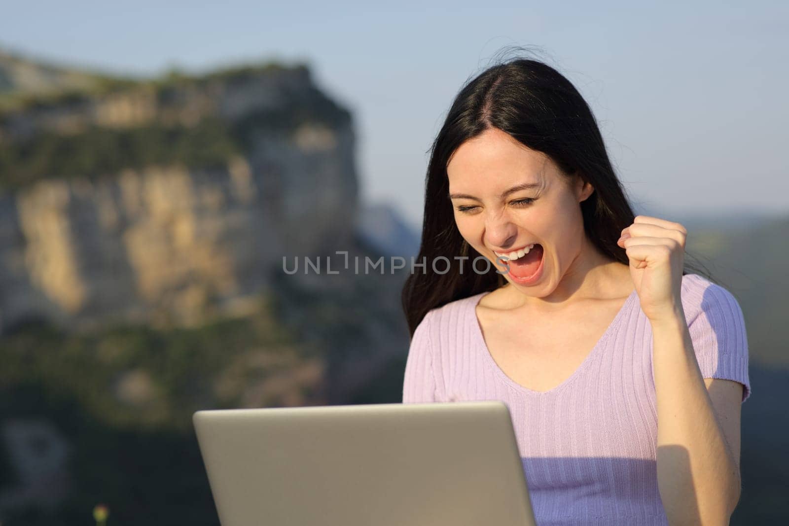 Excited asian woman celebrating checking laptop