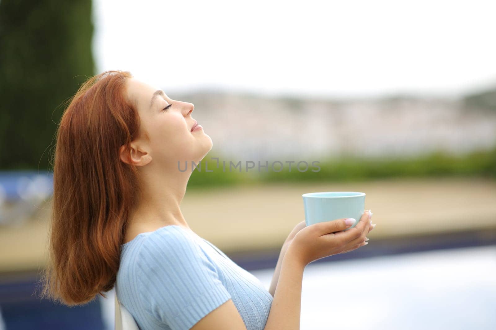 Woman relaxing in a garden holding coffee cup