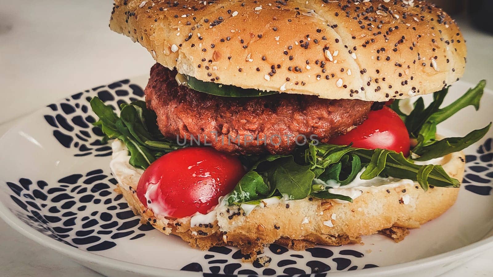 Close-up shot of vegan or plant based hamburger with lettuce tomato and vegenaise in burger bun